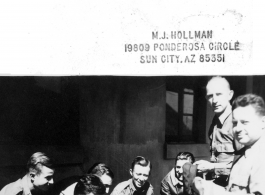 Some 12th Air Service Group personnel squatting in a group in the CBI. CASC. Capt. Dell with hat.  Photo from M. J. Hollman.