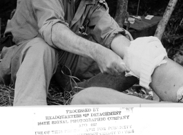 An American doctor treats a leg injury in on site in the forest in the CBI during WWII.  Photo from John E. Clark.