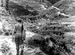 Cpl. Arthur Hedge, of 164th Signal Photographic Company, with carbine over shoulder, hikes trail towards Salween River campaign, 1944.