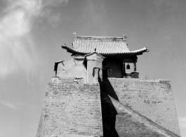 A structure in northern China, elevated on a brick tower set upon the remnants of a town wall. During WWII. This is almost certainly a temple.