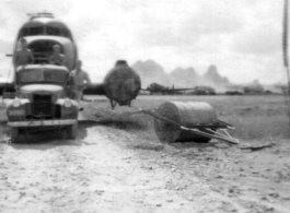 American mechanics of the 12th Air Service Group carefully ease the fuselage of a C-47 past a large concrete roller. In Guangxi, China, during WWII.