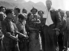 An American flyer--piece of silk parachute slung around his neck--is surrounded by appreciative crowd of Chinese people in Guangxi, China. During WWII.