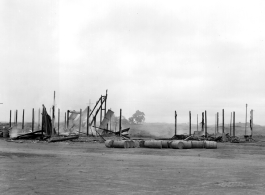 Burned building and fuel barrels at an American base, likely at Guilin, China.