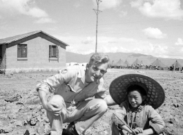 Luliang (China), Bert Krawczyk and a young boy at the air base at Luliang, ca. 1943-1945: "Bert Krawczyk at Luliang in Yunnan Province, China. This young Chinese boy was part of the thousands of local people from the town and surrounding area that worked at the air base. The Operations building to the left was constructed by the Chinese of mud brick. Tents in the background were hastily set up to house retreating American and Chinese soldiers after the loss of forward airfields in central China. The boy (ag