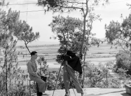 A photographer takes a portrait photo of an American serviceman. Yangkai valley in the background. During WWII in SW China. 