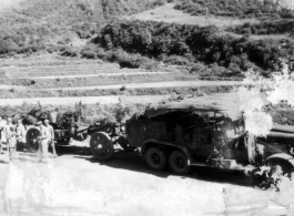 GIs and Chinese soldiers chat near a large Chinese transport truck towing a camouflaged artillery piece in SW China during WWII. 