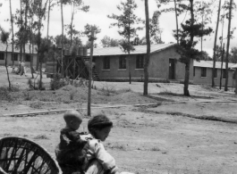 GI explorations of the hostel area at Yangkai air base during WWII: A woman carrying an infant works.