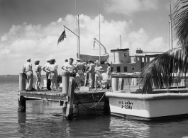 A GIs and civilians play at the waterside, likely in Florida, during WWII. Note U. S. Army boats #J-2361 & #T-171.