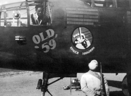 Lloyd Kershaw works in the bombardier's compartment of "Old 59". This B-25C of the 491st Bomb Squadron had completed 221 combat missions, as represented by the 'bomb' symbols painted above the Squadron's ' Ringers' insigne. Kershaw was preparing the aircraft for its trip back to the USA. An unidentified "Old 59" crew member stands beside a Chinese soldier, who would have been guarding the aircraft through the night.