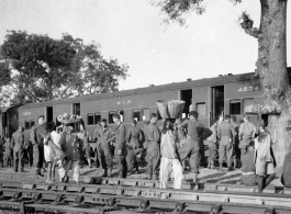 GIs and local vendor mingle during a rest stop on the train in India during WWII.