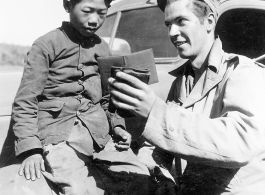 At the Tengchong cutoff: Convoy driver Pfc. John R. Floyd shows a kids a picture of his wife.  Yunnan Province on March 4, 1945.  Photo by T/Sgt. Greenberg.  Passed by William E. Whitten.
