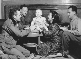  T/Sgt. Franklin E. Ditto, Sgt. Raymond F. Brunner, ARC civilian aide Lucy, and Cpl. Theodore A. Kobel play with Virginia Elizabeth Porter. Yunnan Province on December 15, 1944.   Photo by Pfc. Thomas F. Melvin.  Passed by Emanuel Goldberg.