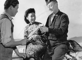 Chinese candymaker at the Russian bakery offering some of the now locally manufactured candy which is soon to be sold in US Army Post Exchanges, at APO 627, to Maj. Robert E. Envell. Sitting by is MME Wei Chen-ko, wrapping the peanut candy. Yunnan Province on December 15, 1944.   Photo by Pfc. Thomas F. Melvin.  Passed by Emanuel Goldberg.