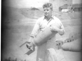 Sam Hansen holds a bomb, probably near Chenggong air base, Yunnan, China. During WWII.