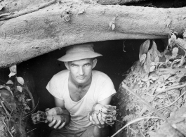 Engineer of the 797th Engineer Forestry Company poses in an old bunker with discarded Americans mortar shells in hand, similar to US M49A2 60MM mortar.  During WWII.