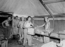 Burma Road engineers pick up goodies at camp in Burma--including Butterfinger bars, soap, chocolate syrup, etc.  During WWII.