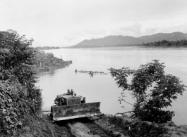 Caterpillar pulling logs raft up bank from river.  797th Engineer Forestry Company in Burma.  During WWII.