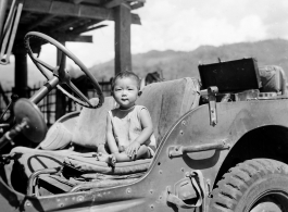 Kid sits in jeep in Burma.  Near the 797th Engineer Forestry Company.  During WWII.