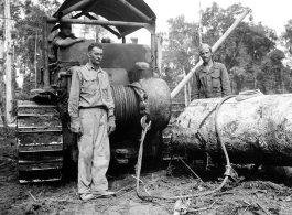 Bulldozer using cable choker to pull log through mud in Burma.  797th Engineer Forestry Company in Burma.  During WWII.