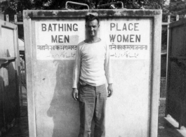 Irwin Schneckloth of 2005th Ordnance Maintenance Company, 28th Air Depot Group, poses with curiosity in front of public shower stall, likely in India. During WWII.