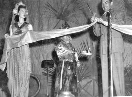 Movie star Melvin Douglas, part of USO troupe, cutting the ribbon during a USO performance at Gushkara, India, during WWII.