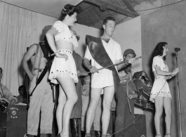 Variety skit at a USO show in Gushkara, India, during WWII.  The boxes in front of the band players are labeled 748th ROB (748th Railway Operating Battalion).