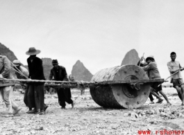 Chinese workers pulling a large roller at a base  in Guangxi province (probably Liuzhou, but maybe Guilin), China. 