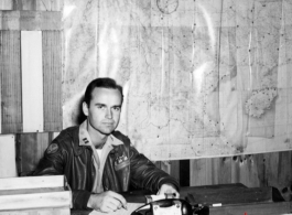 An American soldier with "Flanagan" (花纳根）on his jacket in the CBI. Notice the "491st Bomb Squadron daily status" on the wall behind him.  This is a photo of Captain James Flanagan who was the operations officer of the 491st Bomb Squadron. This photo was taken probably at Yangkai Airbase in late 1944. Please see: http://www.usaaf-in-cbi.com/ for additional information. (Thanks to sds)  From the collection of Wozniak, combat photographer for the 491st Bomb Squadron, in the CBI.