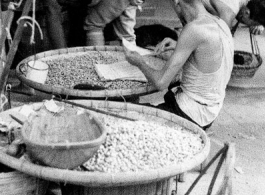 Local people selling peanuts in a market in Yunnan province, China. During WWII.