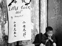 "Little Tiger Joe," Chinese refugee baby adopted by one of the units of the 14th Air Force, is shown here framed by an ancient Chinese doorway, during WWII in China.