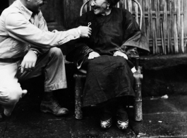 S/Sgt. Steve Wasylyshyn, 279 Garfield St., Johnstown, Pa., inspects jewelry an 82 year old Chinese woman has again brought out now that the Japanese have left her village.  She explained that she hid them when the Japanese first came and has kept them that way through all of their occupation.