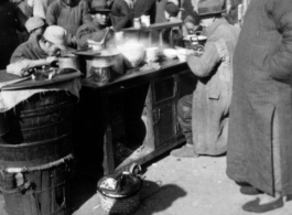 Local people get a tasty breakfast at a breakfast stand at a market somewhere in China during WWII.  Hickey.