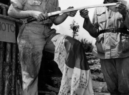 An American GI and and Chinese soldier examine Japanese flag and sword. During WWII in the CBI.
