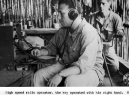High speed radio operator working from a bamboo hut in the jungle, the key operated by his right hand. His partner supplies the power from a generator with a two-handed crank.  US Signal Corps photo.
