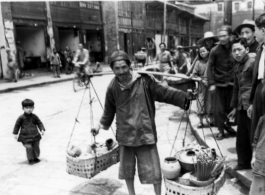 A Chinese vendor carries his goods on a shoulder pole in the CBI during WWII.  Photo by C. W. Leipnitz.