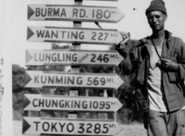 An American GI poses next to a heavily loaded sign post along the Ledo Road during WWII.  Photo from C. C. Carter.