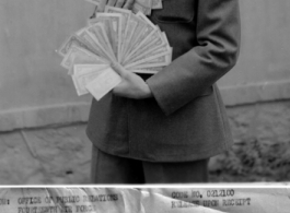 Pfc Eugene Riede holds a large collection of Chinese currency, in China, during WWII.