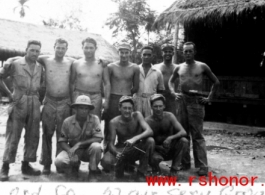 Men of the 1791st Ordnance Company, 52nd Air Services Group, pose for a photo in front of huts, during WWII.