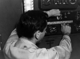 GI works a radio during flight in the CBI during WWII.