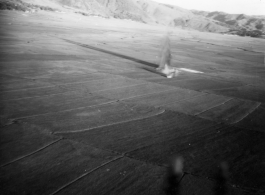 Image of a very odd explosion near Tengch0ng--out in the  middle of a rice paddy. What this a bomb blast or an aircraft crash? Image taken from B-25 Mitchell bombers during battle with Japanese ground forces, flying near Tengchung (Tengchong), near the China-Burma border in far SW China.