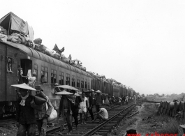Fleeing people on (and on-top) of train during Chinese civilian evacuation in Guangxi province, China, during WWII, during the summer or fall of 1944 as the Japanese swept through as part of the large Ichigo push. During WWII.