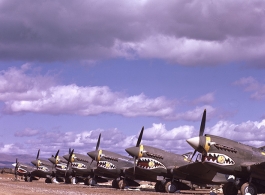 P-40Ks parked in a row in China during WWII, probably in Yunnan province, displaying the 26th Fighter Squadron "China Blitzers" badge on their sharkmouth.
