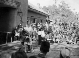 Celebrities (including Ann Sheridan hamming it up with Ben Blue, and Ruth Dennis playing an instrument in this shot) perform on an outdoor stage set up at the "Last Resort" at Yangkai, Yunnan province, during WWII. Notice both Americans and Chinese in the audience for this USO event.
