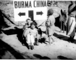 A pipe-smoking GI cuddles a foot-bound Chinese woman against the Burma-China border sign. During WWII.  Image from Emery and Beth Vrana.