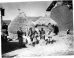 American GIs and people in a local village in Yunnan province, China, threshing grain by striking the rice straw against grinding stones.  From the collection of Eugene T. Wozniak.