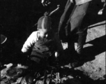 A small child plays at a charcoal hearth in China during WWII. These might be refugees at Liuzhou.