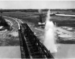 An aerial photograph of a railway bridge being bombed--a near miss--by the 491st Bomb Squadron in Yunnan or Indochina, during WWII.