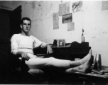 View inside barracks for two GIs in Yunnan, China, during WWII--GI sitting at desk.