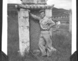 Charles Klaes leans against back of tombstone at base at Yunnan, China. During WWII.