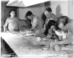 "Mosaic laying" at photo lab of the 24th Mapping Squadron--cutting and pasting numerous high-resolution aerial images together onto a board to create a wide view. June 10, 1944.
